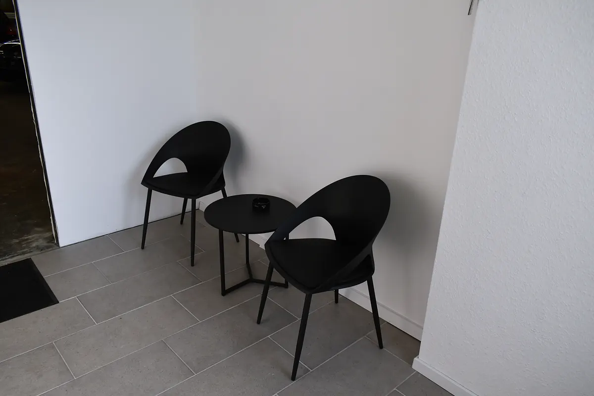 Zwei Stühle und ein kleiner Tisch im Kundenbereich der Werkstatt